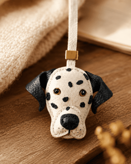 Macro photo of handmade leather Dalmatian dog bag charm with black spots, black ears, white strap, gold slider, and leather grain