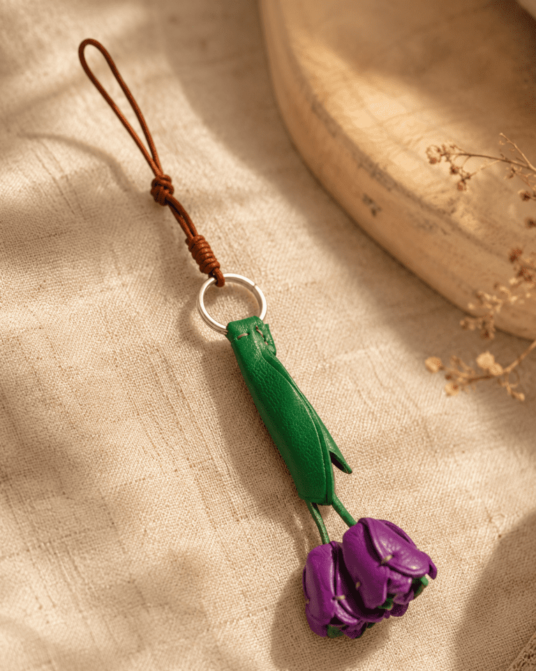 Handmade leather purple tulip bag charm close-up on linen fabric
