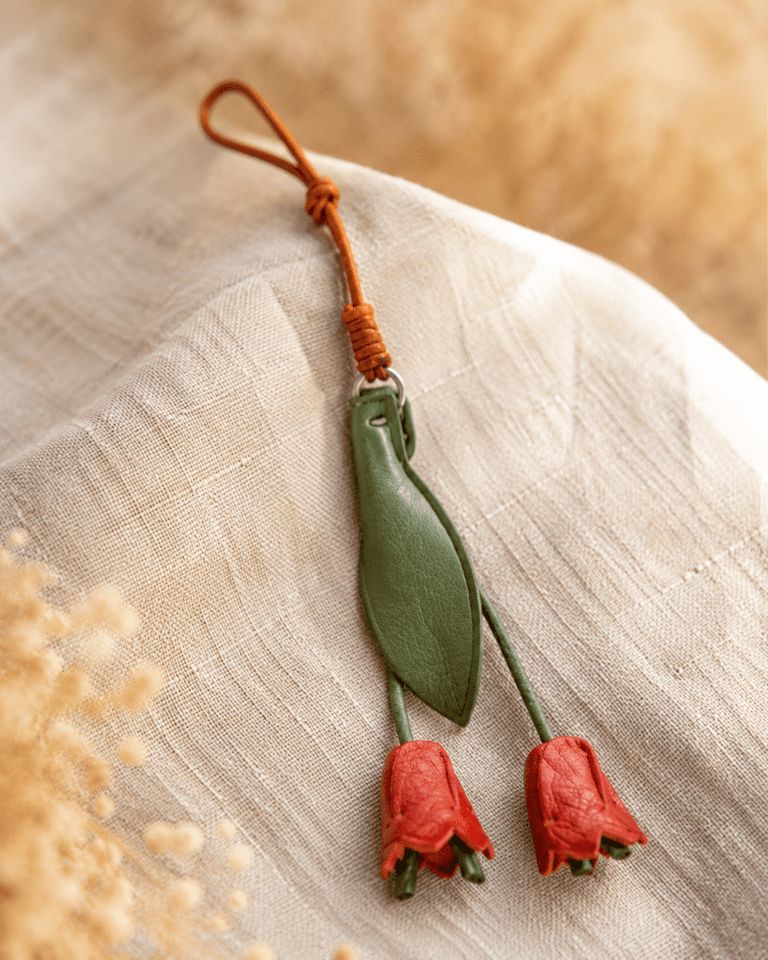 Close-up of a handmade leather red tulip bag charm on linen fabric