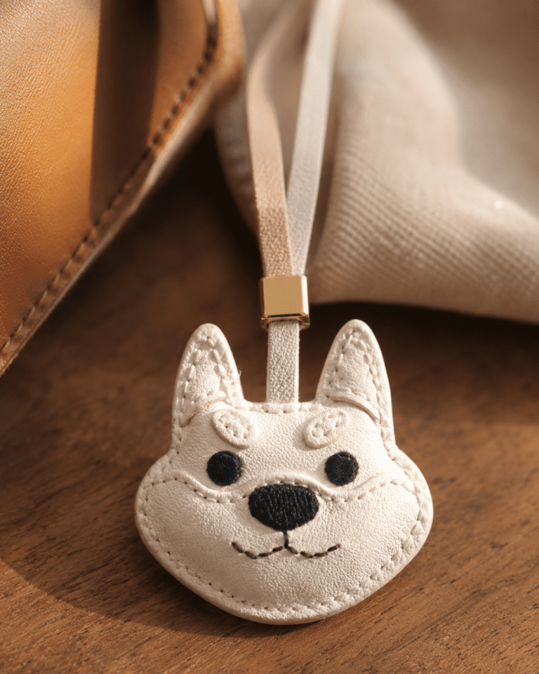 White leather dog face charm on table with coffee cup, cake, and open book, cozy sunlight