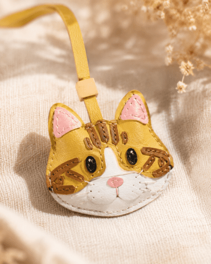 Yellow cat bag charm attached to brown handbag, lifestyle cafe scene
