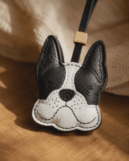 Close-up of handmade French bulldog leather bag charm showing black ears, white face, stitched nose, and leather texture